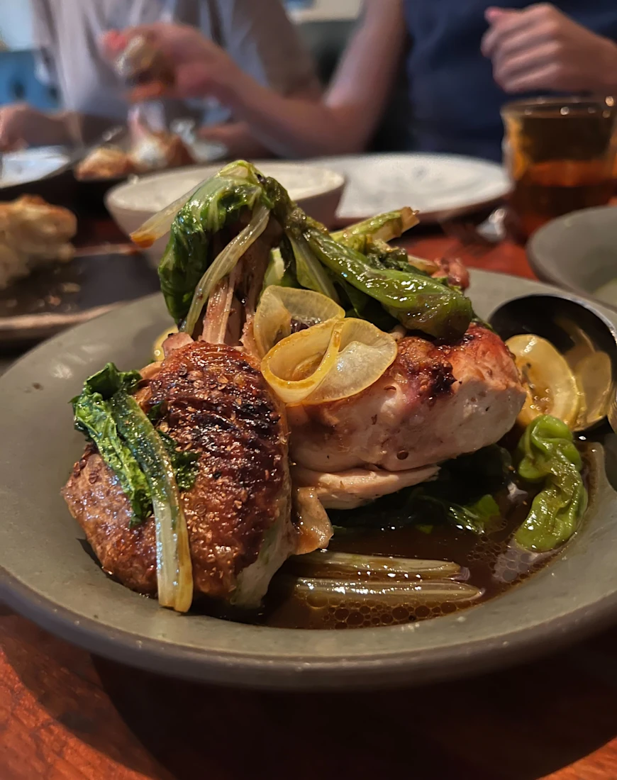 a close-up of cooked chicken topped with grilled shishito peppers