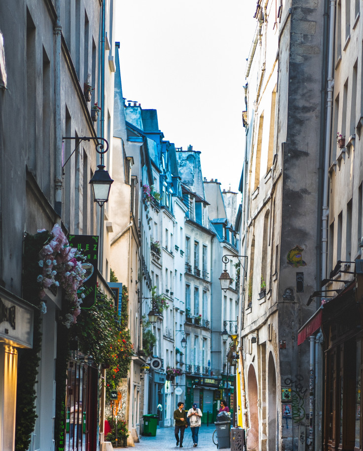 Two people walking down a street in Paris' Le Marais neighborhood. 