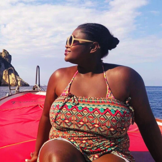 Travel Advisor Anita Ahiadormey in a colorful swim suit on a boat. 