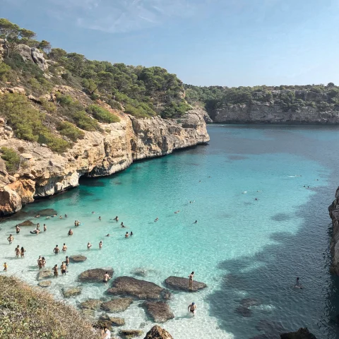 people swimming in turquoise waters surrounded by cliffs