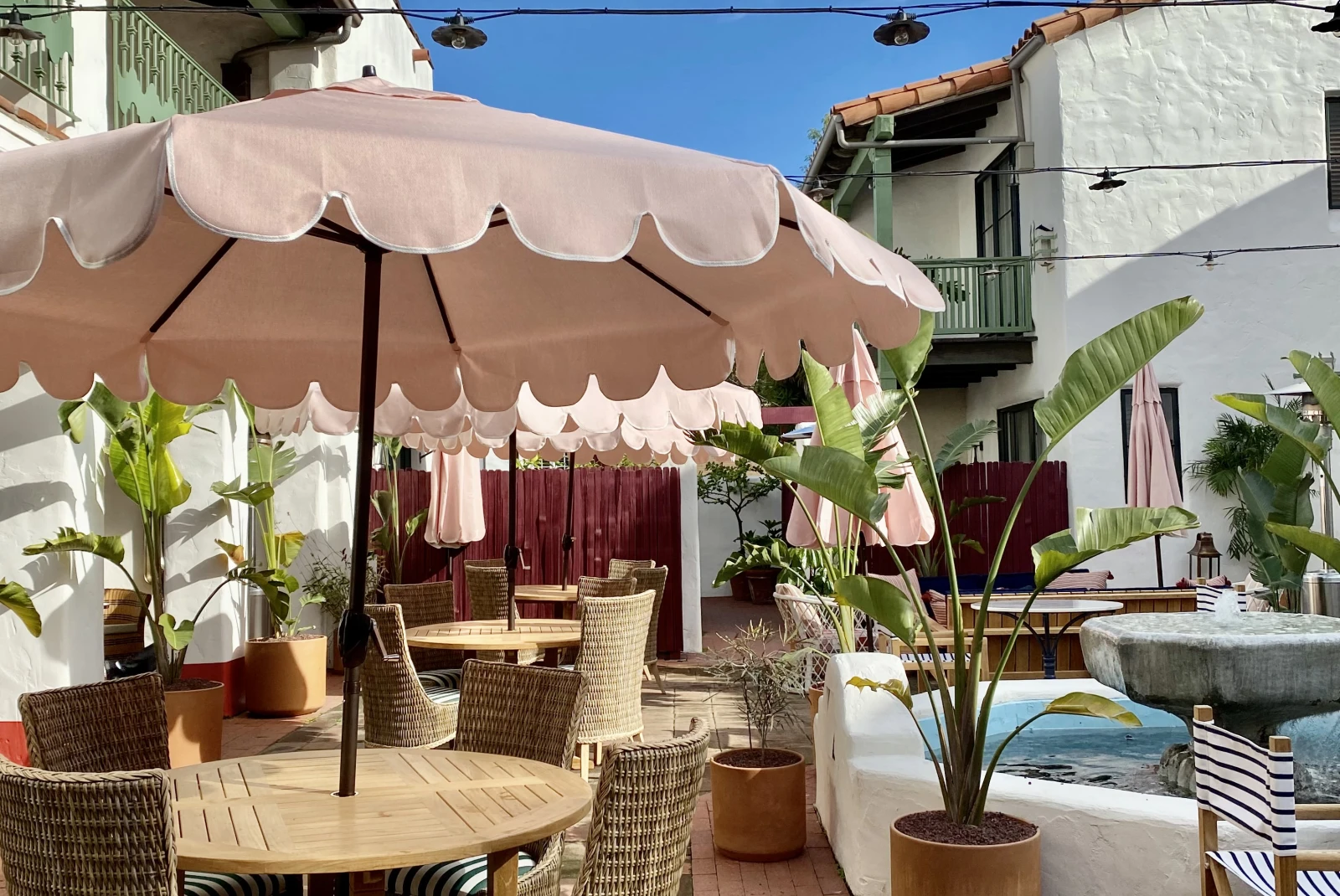 tables with pink umbrellas next to a pool during daytime