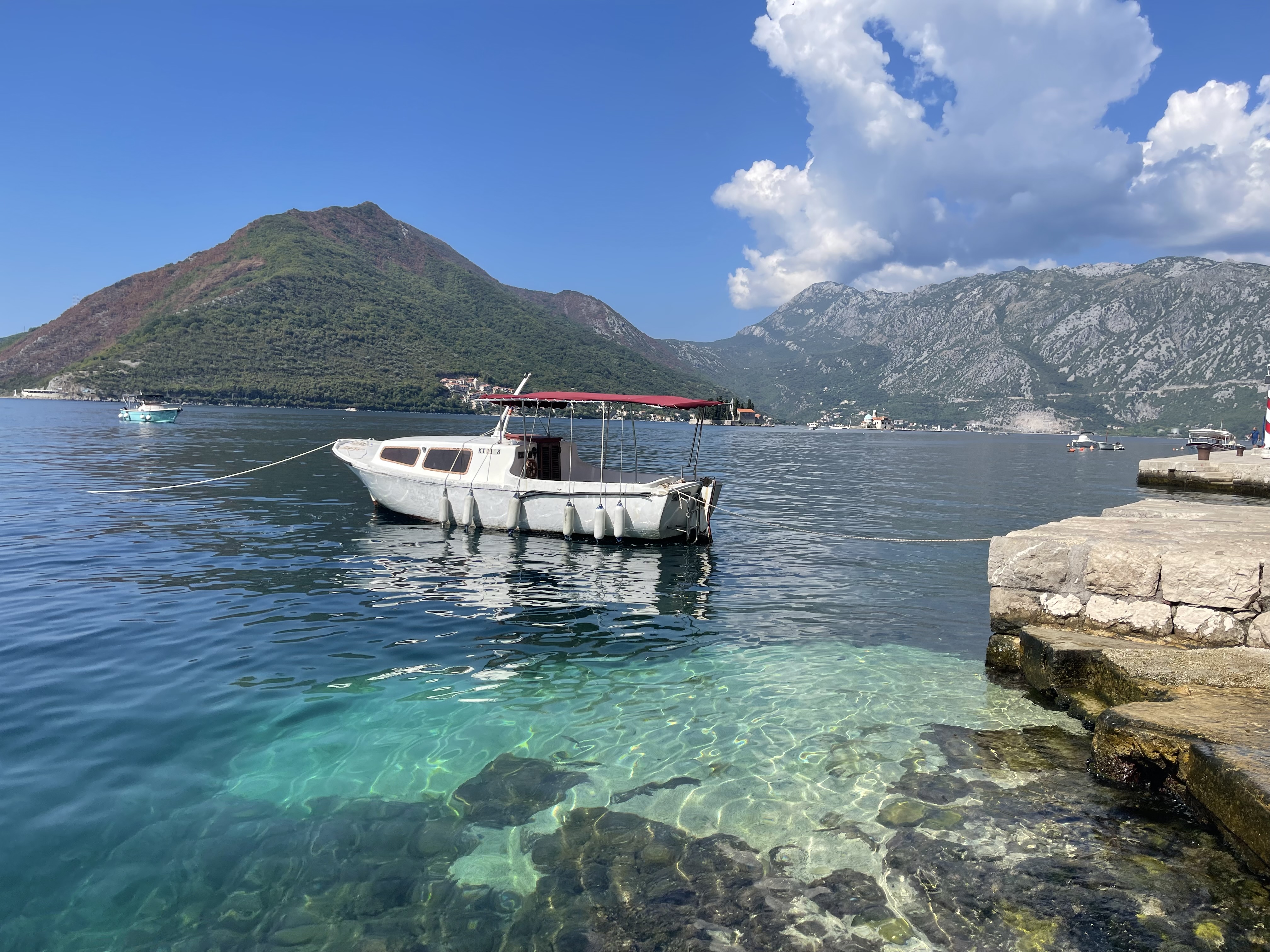 A bayside flanked by mountains and a sailboat. 