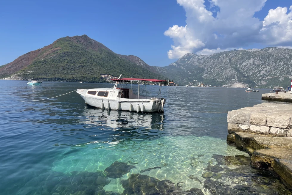 A bayside flanked by mountains and a sailboat. 