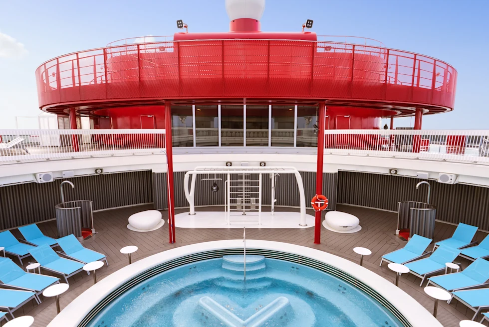 outdoor pool surrounded by blue lounge chairs on a cruise ship deck