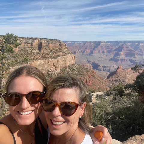 A selfie of two women hiking with canyons in the background.