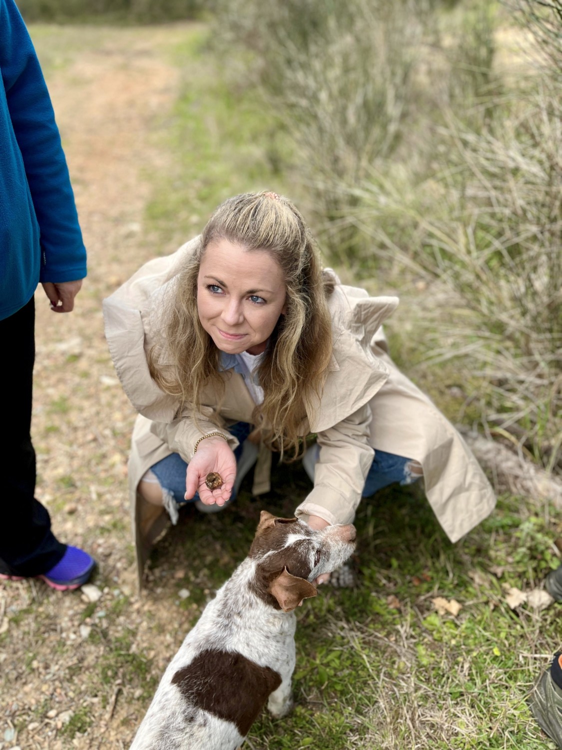 a woman crouches down beside a brown-and-white dog