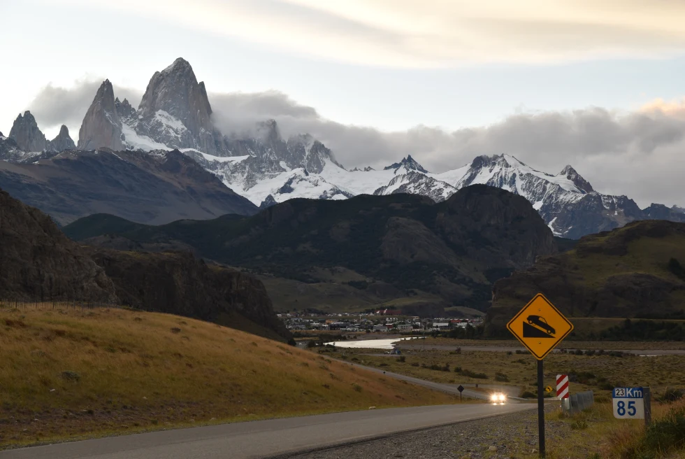 road leading to jagged mountains with cloudy skies