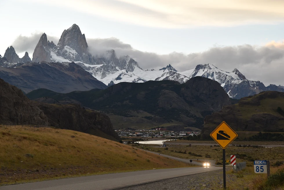 road leading to jagged mountains with cloudy skies