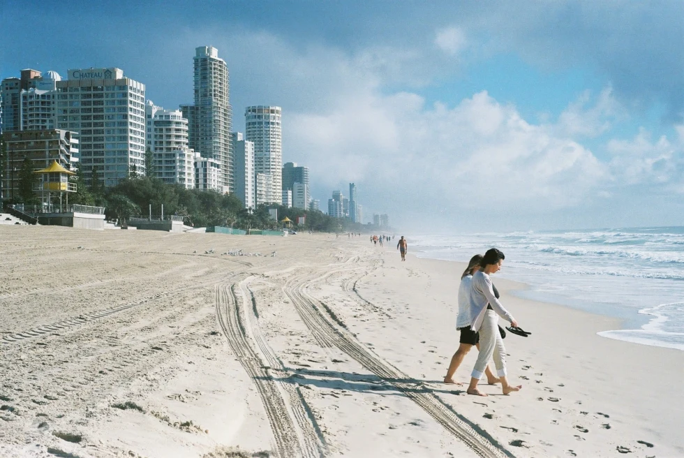 two people walking on the beach with skyscrapers in the background