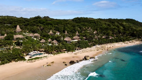 Bird's eye view of the thatched roof of Nihi Sumba Island, a luxury beachfront hotel in Indonesia