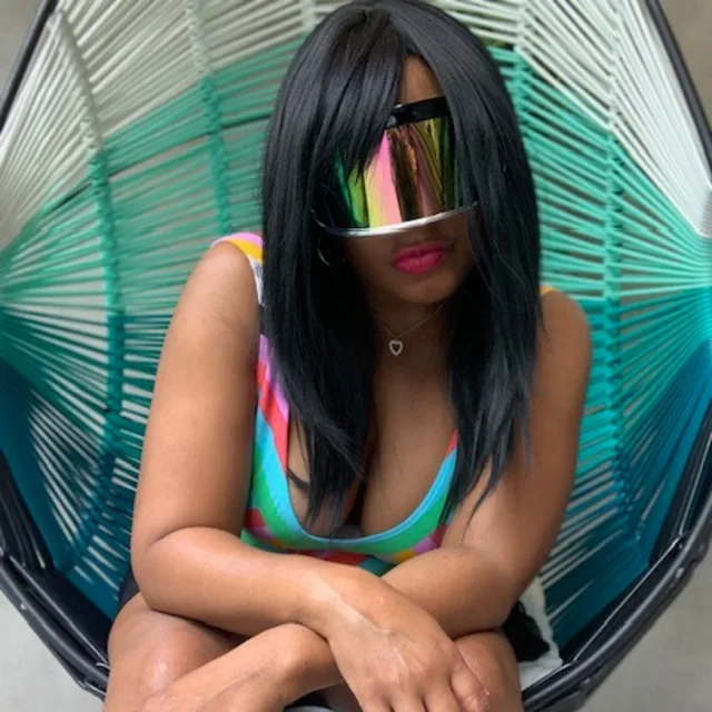 Travel Advisor LaToya Holmes with a blue bathing suit sitting in a chair with reflective glasses on.