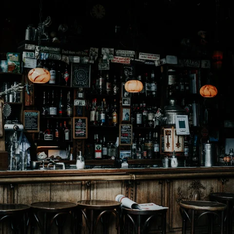 A dark-lit bar with wooden stools in Amsterdam. 