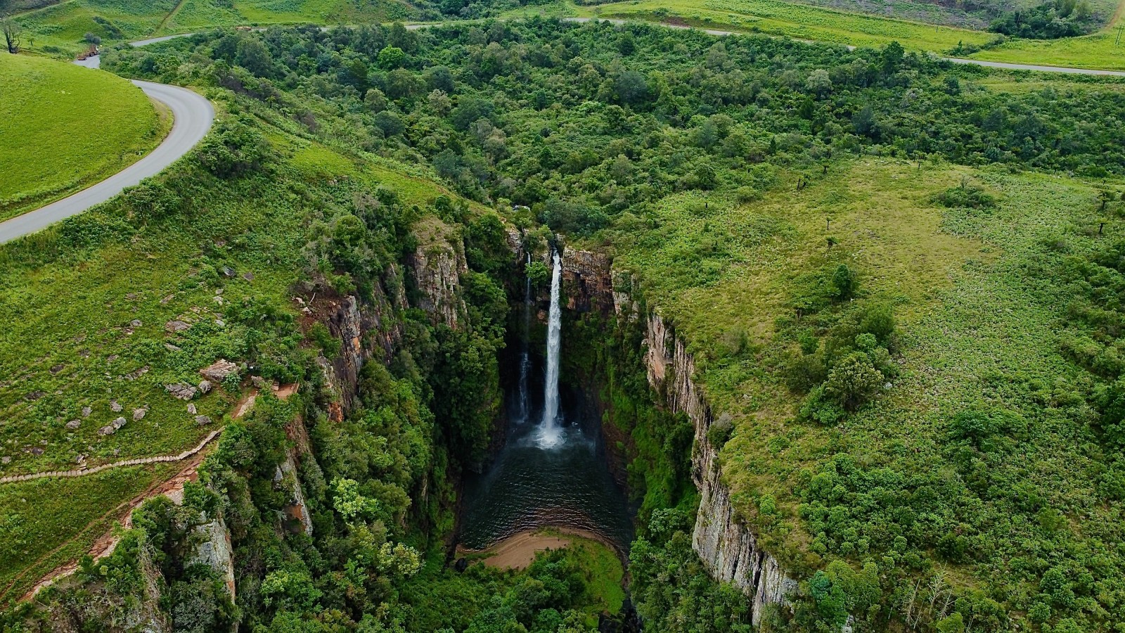 Waterfall surrounded by green mountains during daytime