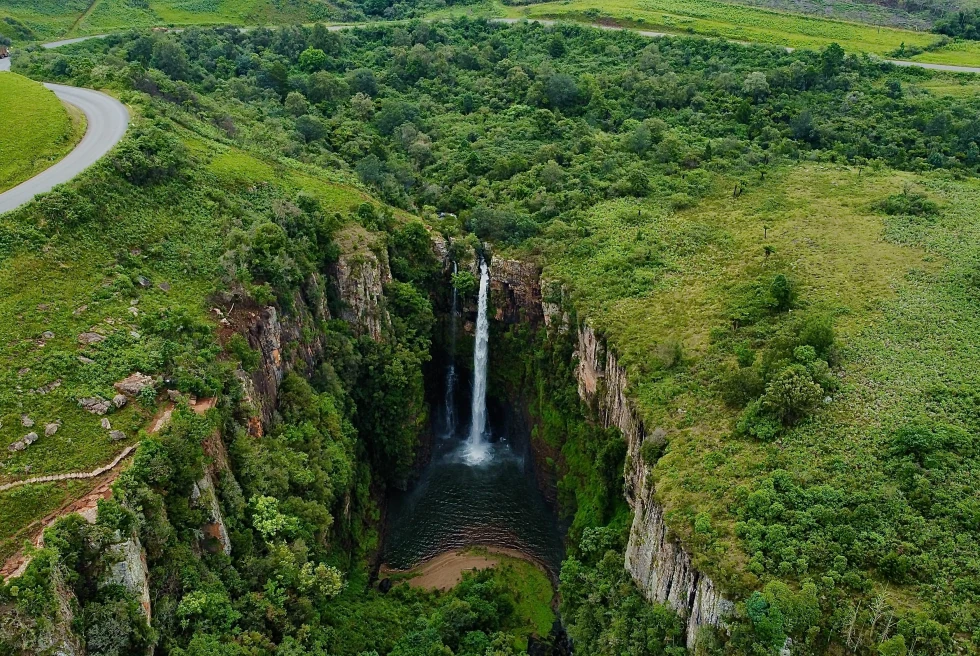 Waterfall surrounded by green mountains during daytime