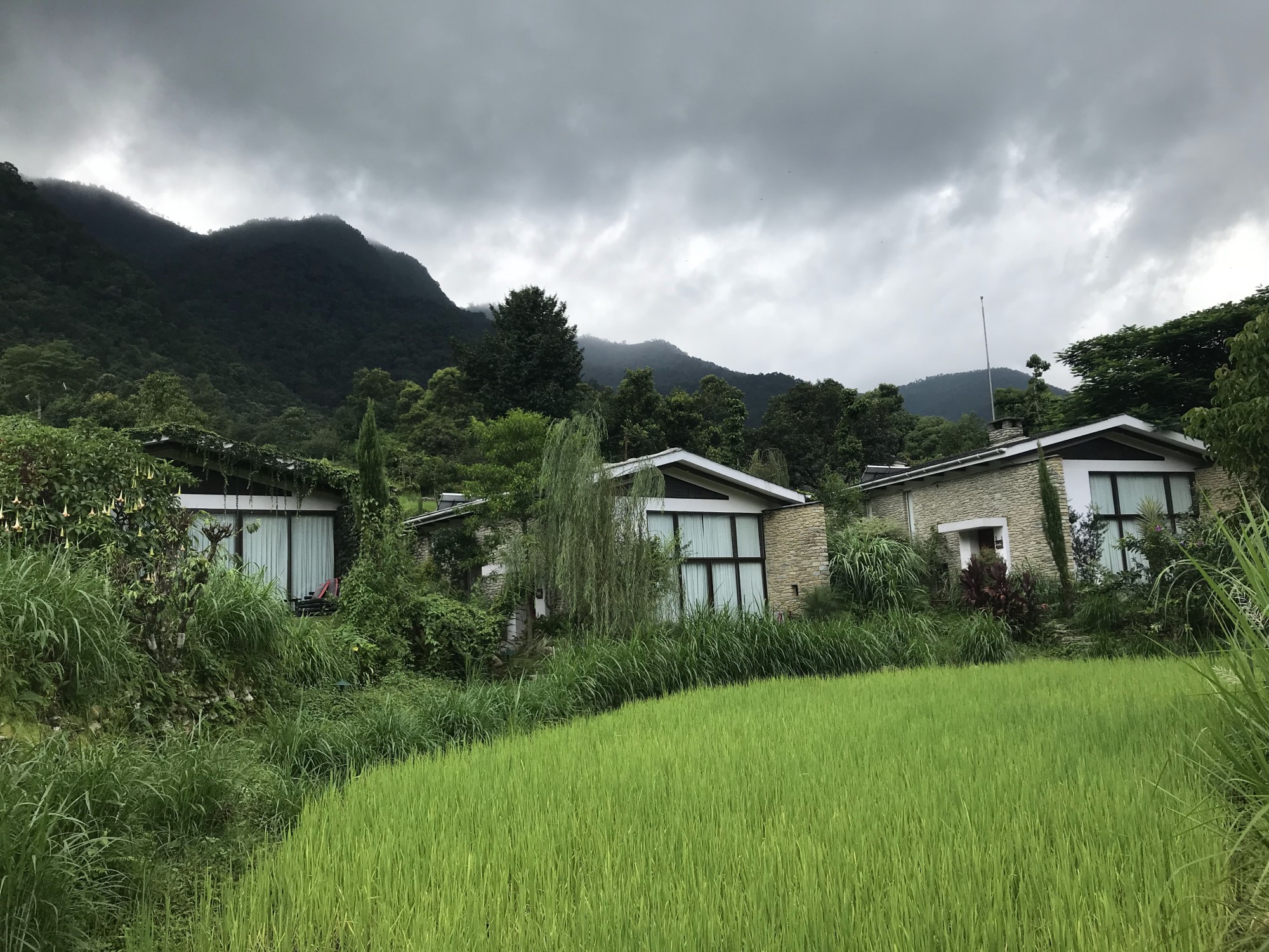 Cabins nested in a valley with green mountains around. 