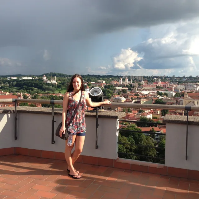 Travel Advisor Jenna Marcinkevicius stands on a roof lookout over a a city with a storm cloud approaching