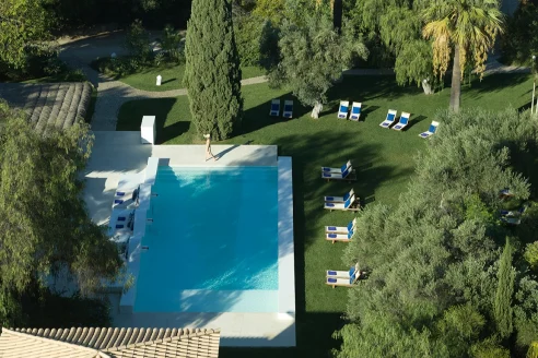 aerial view of a light-blue pool in a lish garden