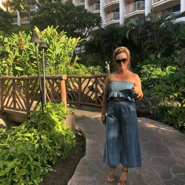 travel advisor wears a blue dress on a path with tropical plants