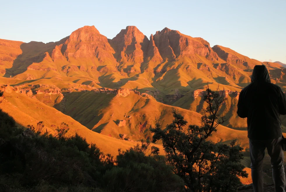 A man standing on yellow mountains at sunset in Southern Morocco. 