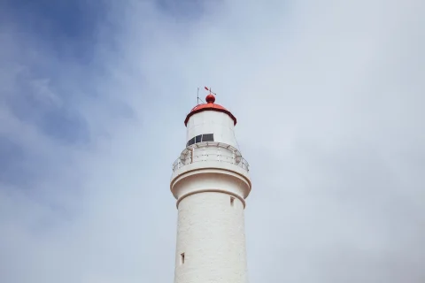 low-angle shot of a red lighthouse with a red top