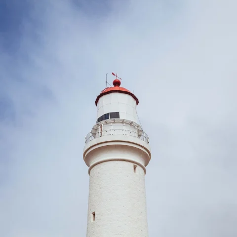 low-angle shot of a red lighthouse with a red top