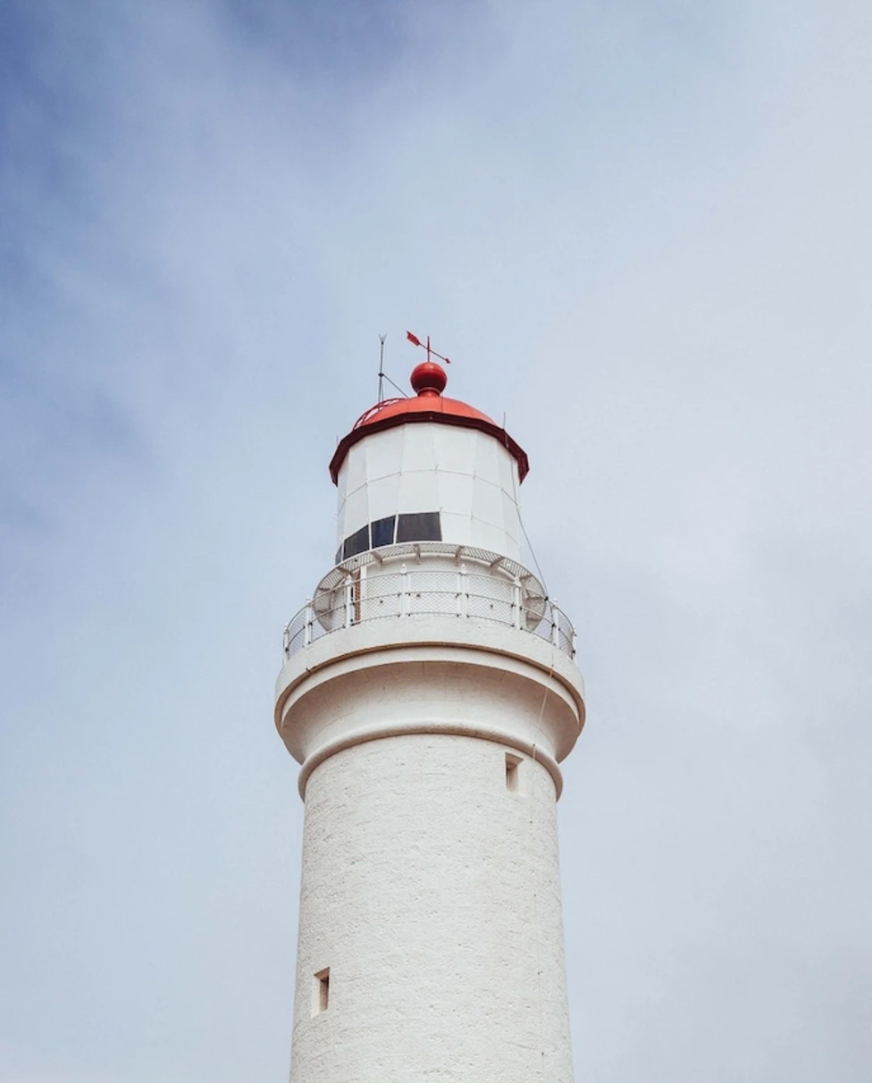 low-angle shot of a red lighthouse with a red top