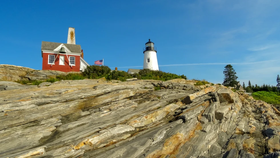 Red house with white lighthouse on rocky hill during daytime
