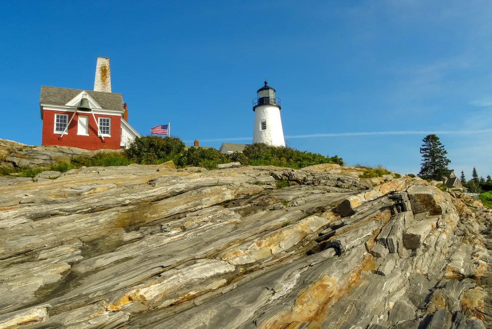 Red house with white lighthouse on rocky hill during daytime