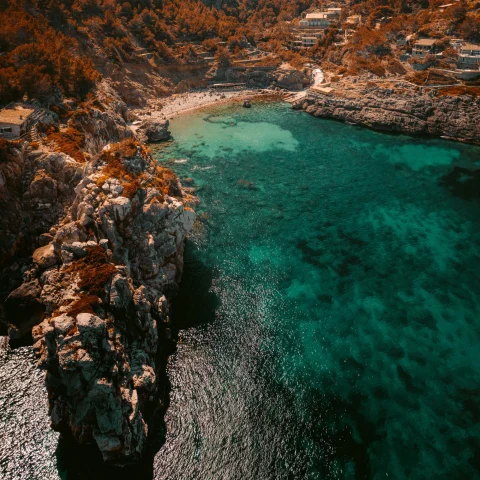 aerial view of vivid blue green waters of an island coast with clifss and mountainrange