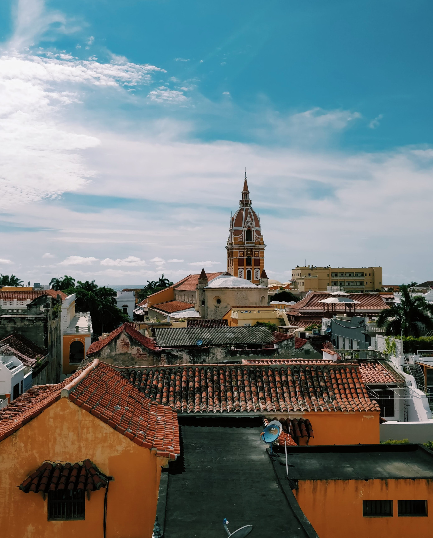 blue skies and white clouds with orange buildings and red roofs city view of Cartagena in Colombia