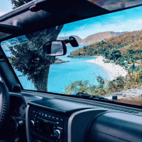 View of blue waters and the beach in St. John out the window of a black jeep