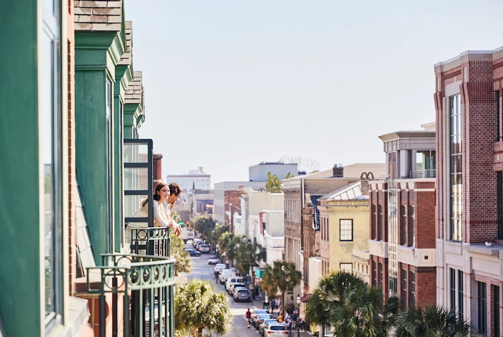 two people standing on a balcony overlooking a city