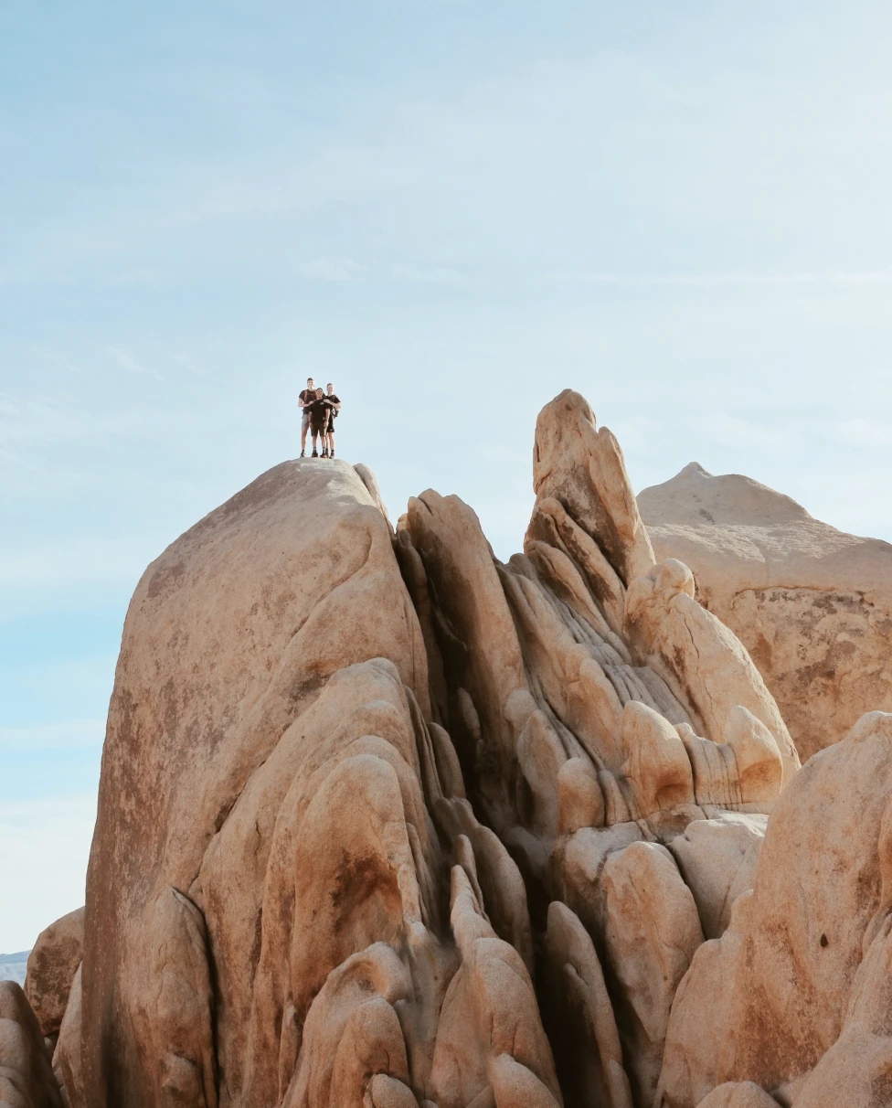 A family of three standing on a large rock in Joshua Tree. 