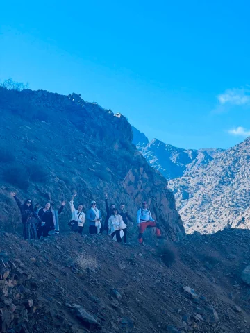 A group of people posing for a photo on the side of the Morocco Atlas Mountains during the daytime.