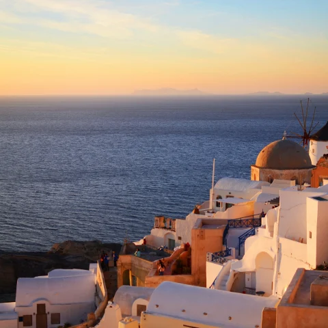 sun setting over the water next to white buildings