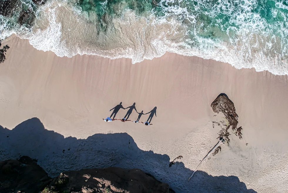 A group of people standing on a sandy beach