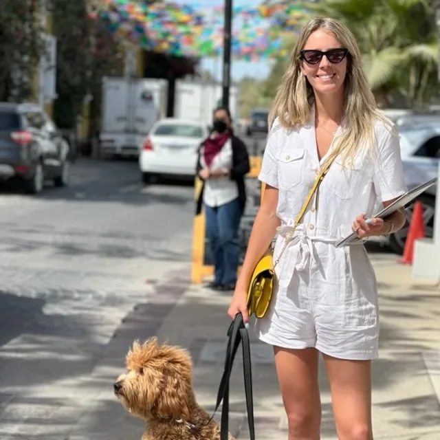 Travel Advisor Shelby Escaba with a white jumpsuit and a golden dog.