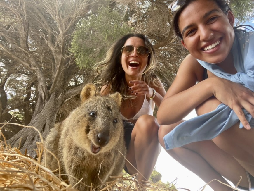 Two people posing with a kangaroo in the wild