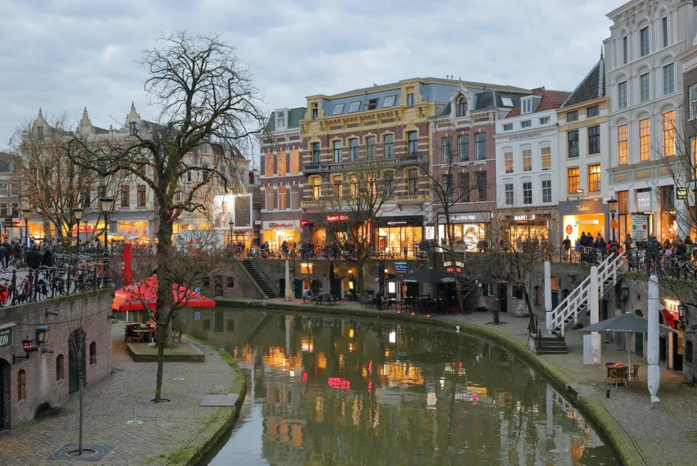an old town with a canal running through in the evening with lit up storefront windows