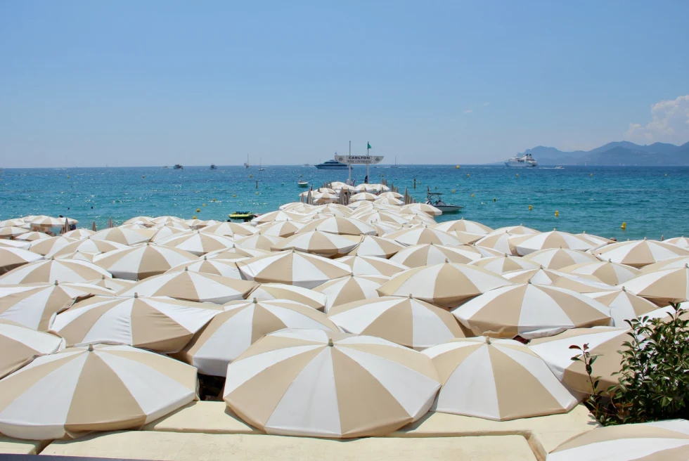 tan-and-white umbrellas covering a beach overlooking the sea