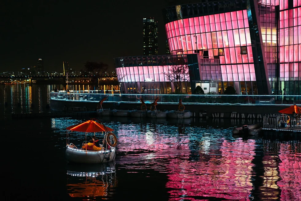 small boat cruises on a river at night
