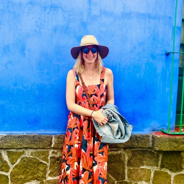 Travel Advisor Mara Bailey-Olson in a red dress in front of a blue wall.