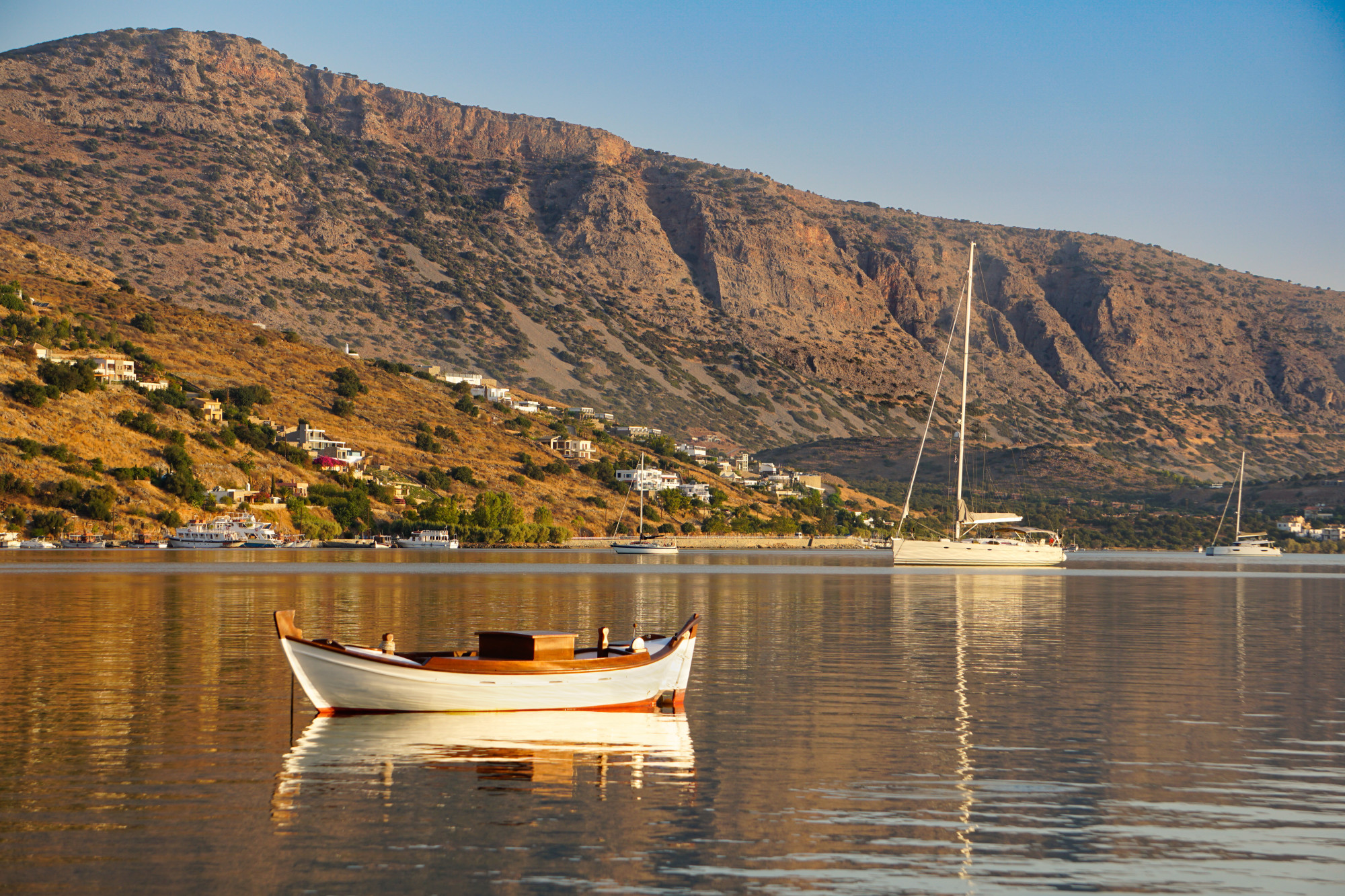 mountains over calm waters of a harbor with a white wooden boat