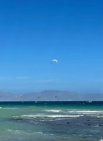 body of water with kites in the sky during daytime