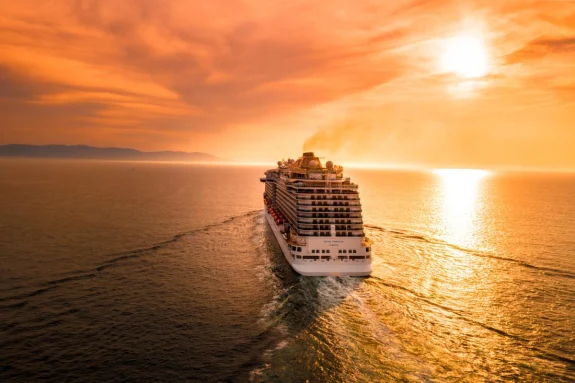 Cruise ship in the ocean during sunset with an orange sky