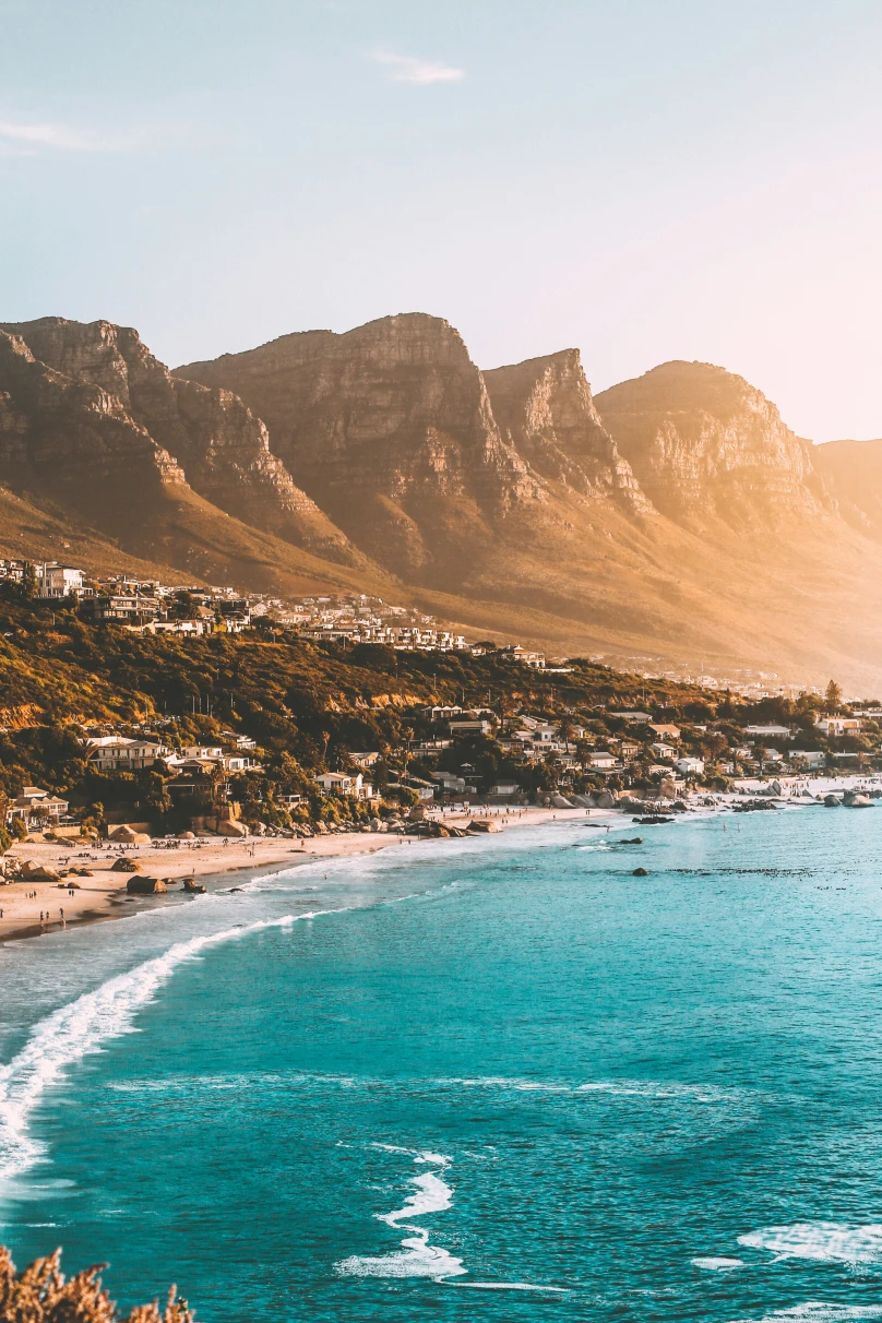 The coastline of Cape Town near Table Mountain, one of the best places to go in South Africa, with buildings on the hillside and turquoise water.