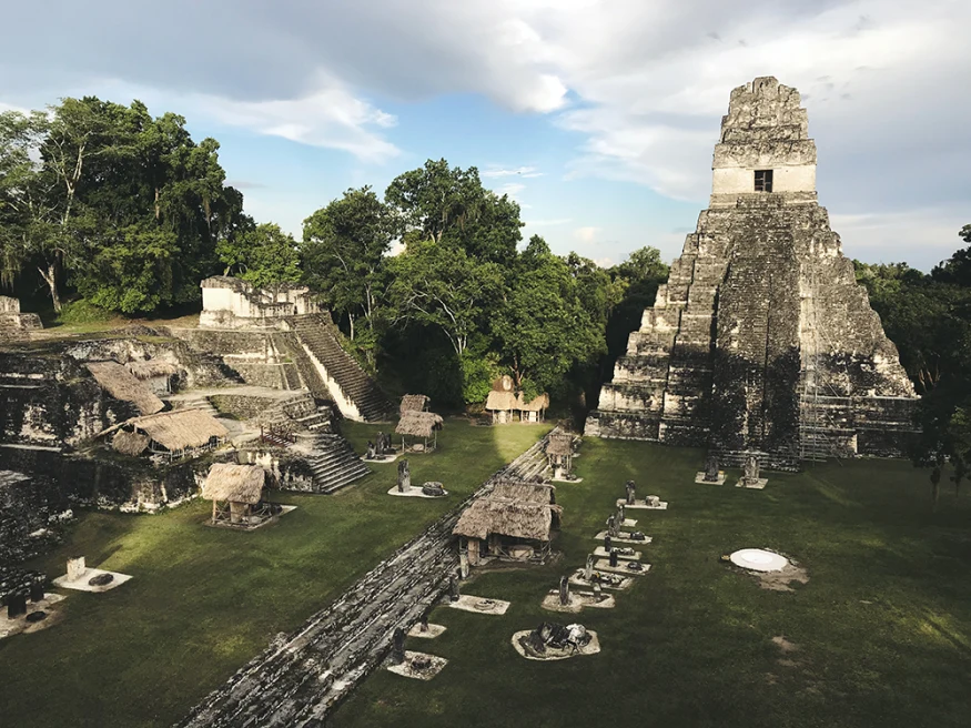 ancient grey and white ruins with green grass and tall trees in Guatemala
