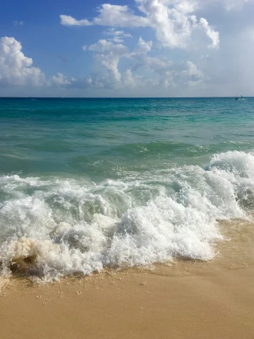 A white sand beach with blue waves crashing on shore outside of the Hotel Riu Palace Riviera Maya Mexico - Playa del Carmen.