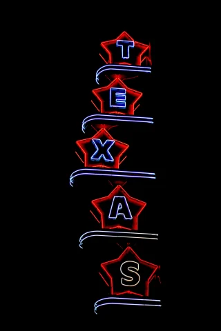 A neon sign of Texas on a building at nighttime.