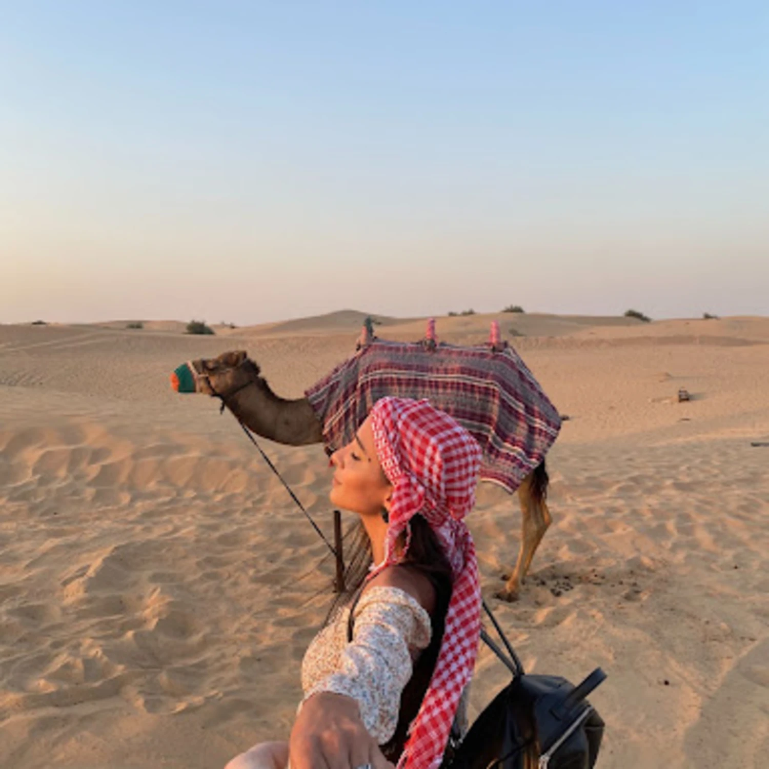 Girl next to camel in desert. 